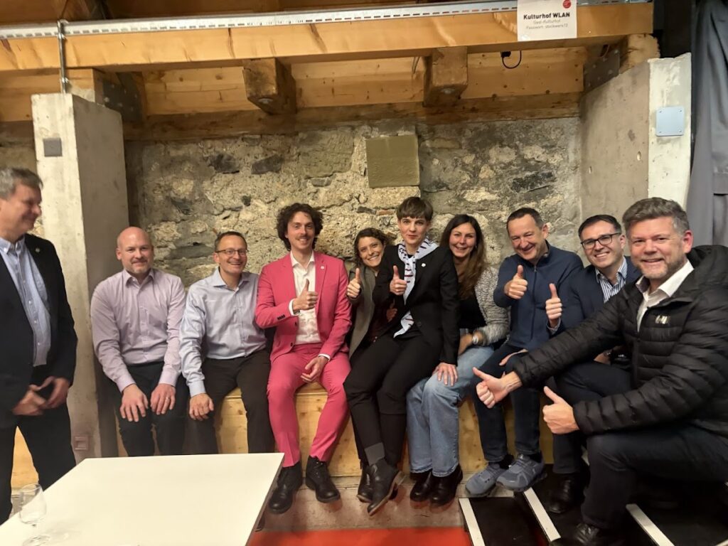 Die Mitglieder der EVP-GLP-Mitte-Fraktion sitzen eng aufeinander in einem Winkel der Schlos Köniz und halten den Daumen hoch. In der Mitte (in pink): Casimir von Arx.